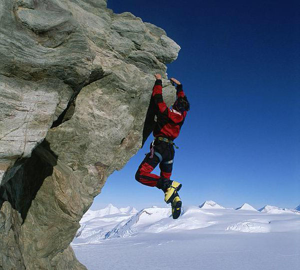 man hanging from a crag